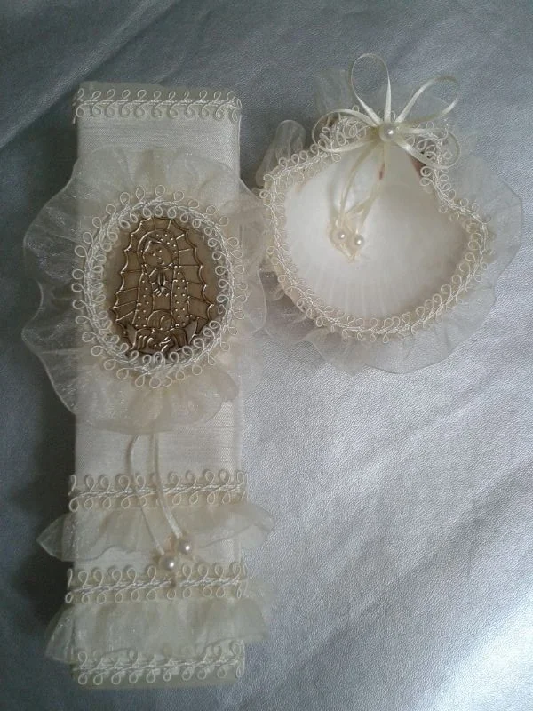 Vela de bautizo marfil con medallón de imagen religiosa, encaje, lazo y concha decorada.