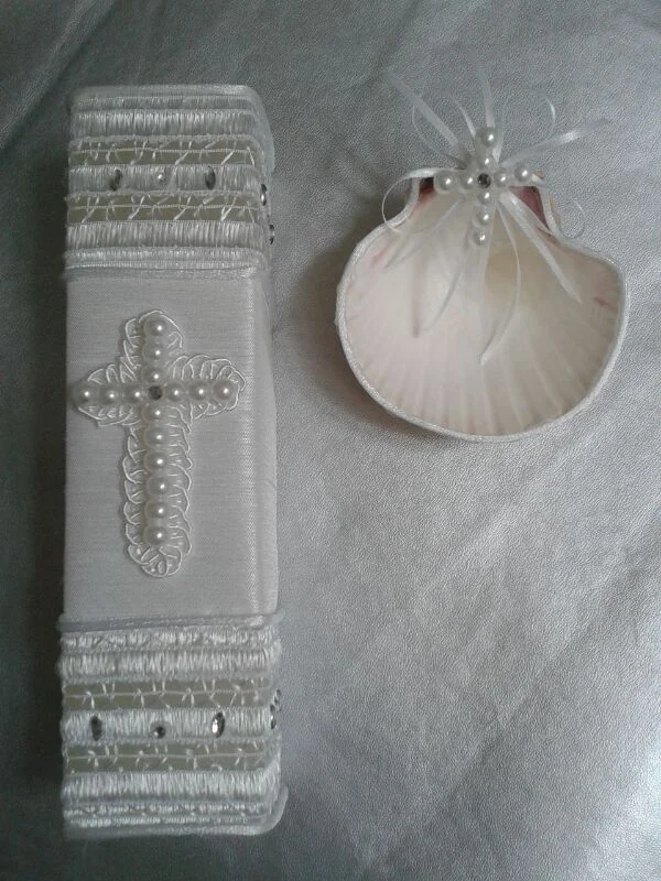 Vela de bautizo con cruz de cuentas, franjas decorativas y concha con lazo y perlas.